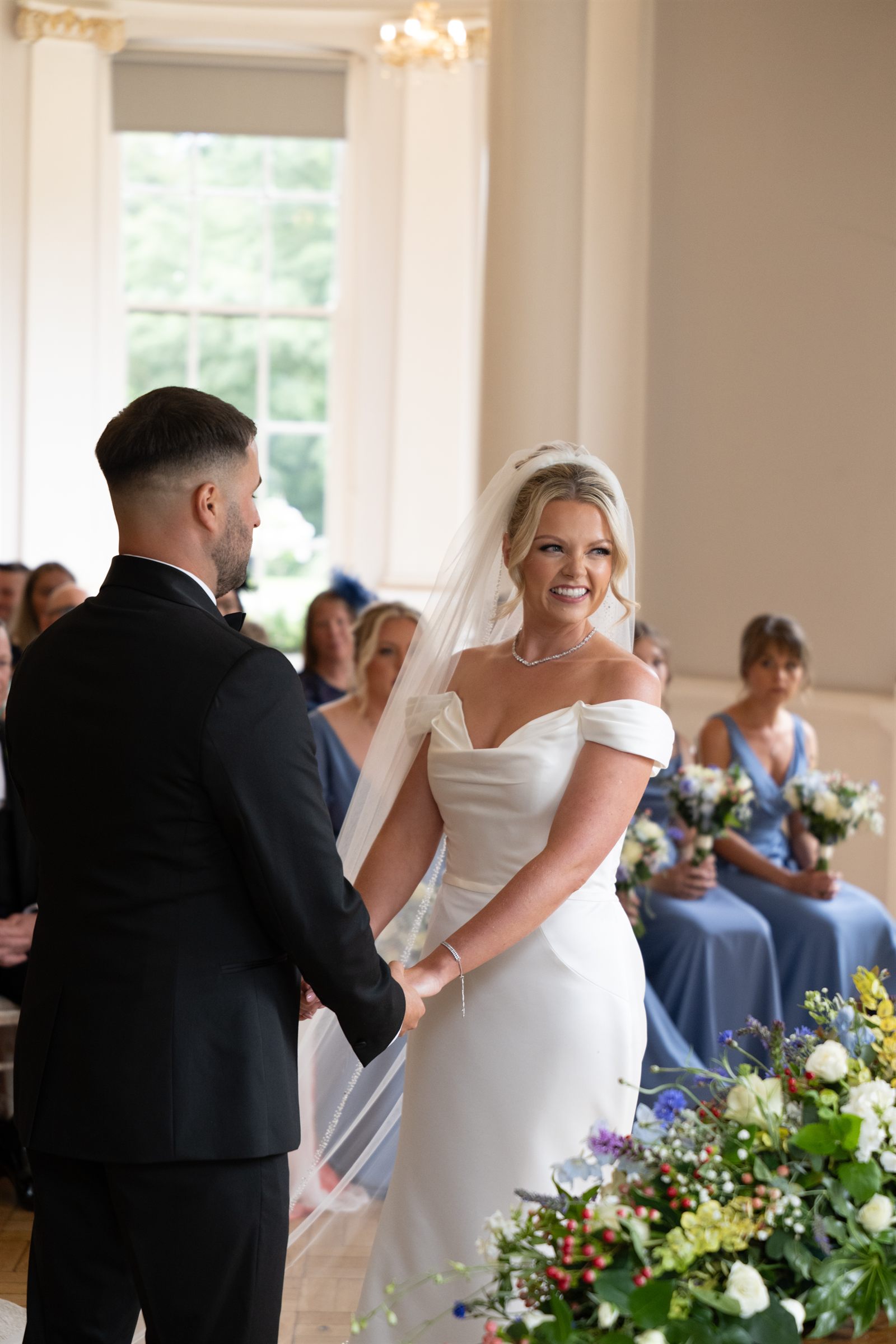 A bride smiling warmly during her wedding ceremony.