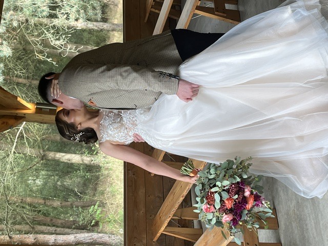 A bride and groom sharing a kiss in a woodland ceremony shelter.